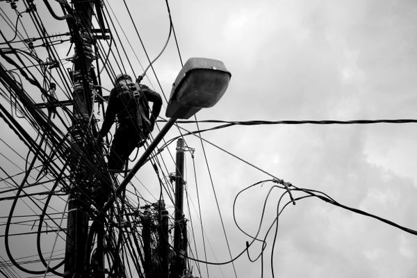 Technician on electric pole fixing fiber optic line